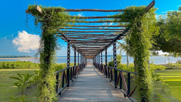 A wooden pathway leading to a gazebo with a view of a body of water. - Hotel Amazon by On Vacation (Leticia)