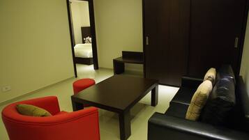 A modern living room with a dark sofa, a red armchair, a black coffee table, and a small table.