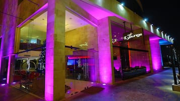 Un edificio moderno con fachada de vidrio y un letrero de neón que dice "Ky Lounge".