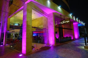 Un edificio moderno con fachada de vidrio y un letrero de neón que dice "Ky Lounge".