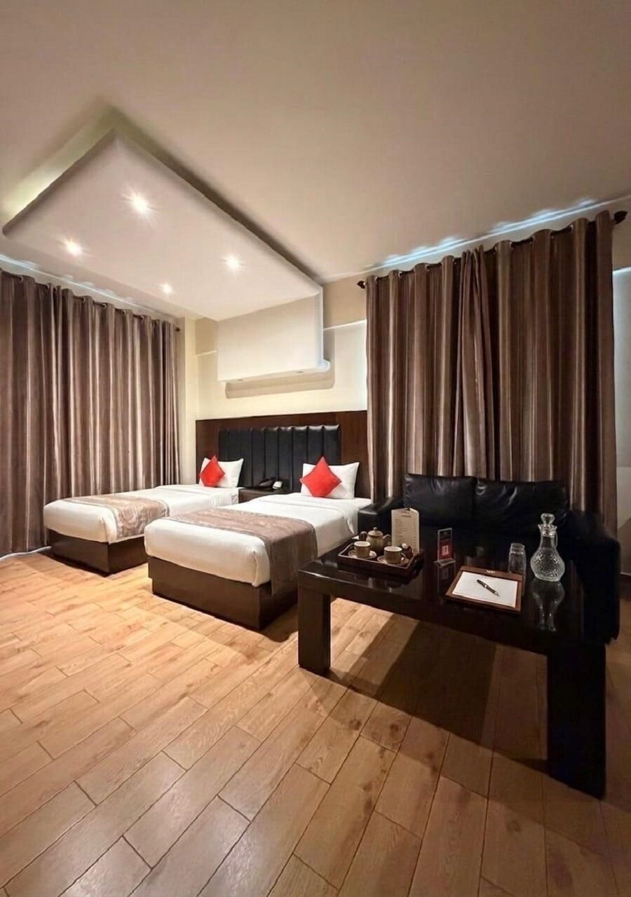 A hotel room with two beds, a coffee table, and a view of the city.