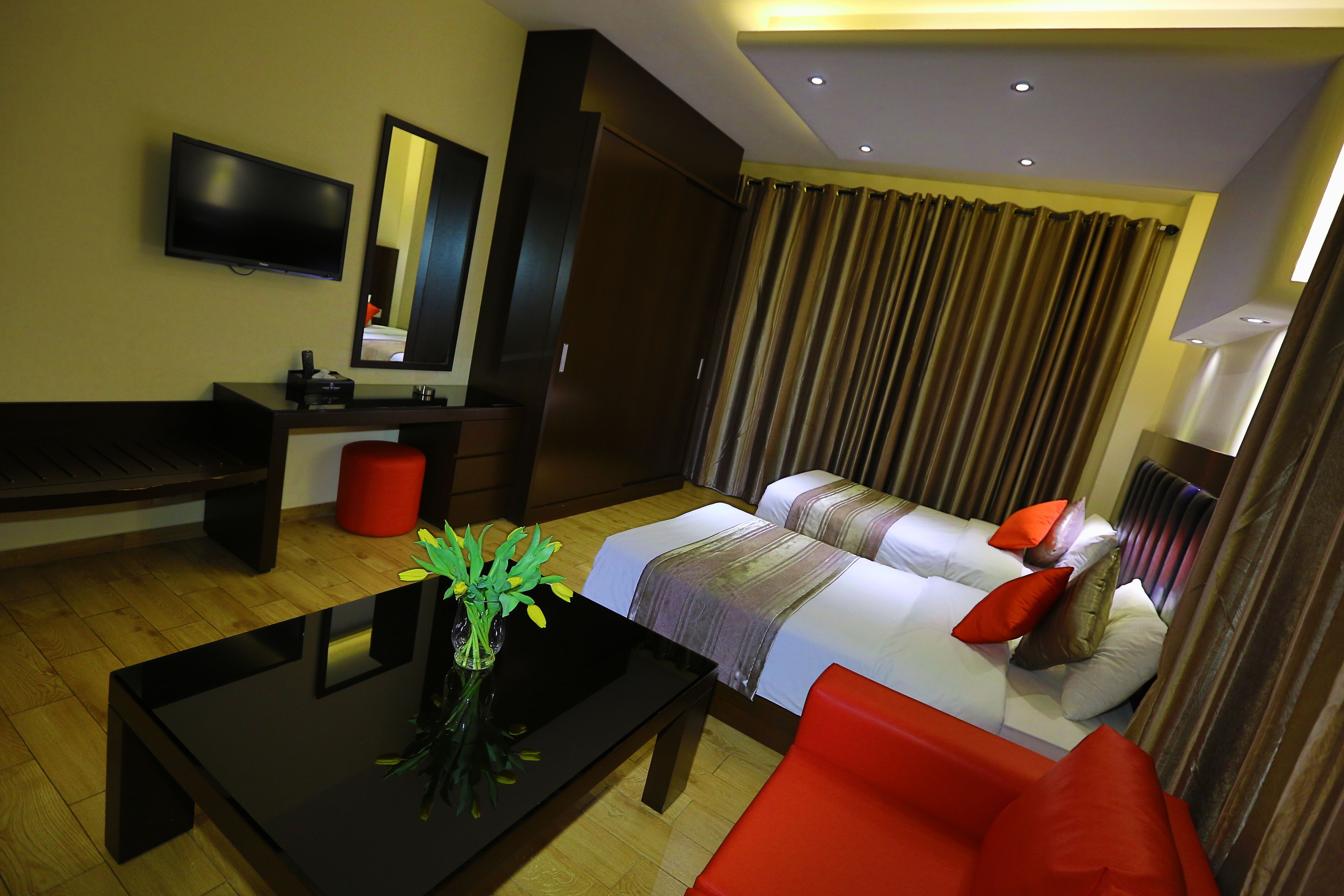 A hotel room with a bed, a sofa, a TV, a desk, and a mirror.