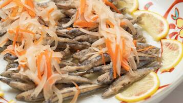 A plate of fish with shredded carrots and lemon slices.