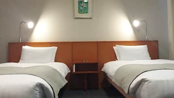 A hotel room with two single beds, a nightstand, a framed picture on the wall, and two bedside lamps.