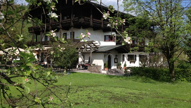 A traditional chalet-style building with a balcony, surrounded by a well-maintained garden and a clear sky. - Alpenhof Landhotel Restaurant (Oberaudorf)