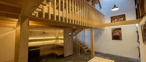 Un interior de madera con un banco, una escalera y una lámpara de pared.