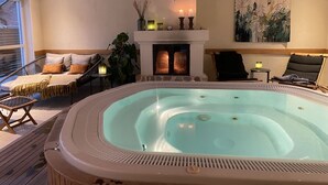 A spa area with a hot tub, seating, a fireplace, and a painting on the wall. - Brösarps Gästgifveri & SPA (Brosarp)