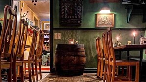 A wooden dining table with chairs, a barrel, and framed pictures on the walls. - Brösarps Gästgifveri & SPA (Brosarp)