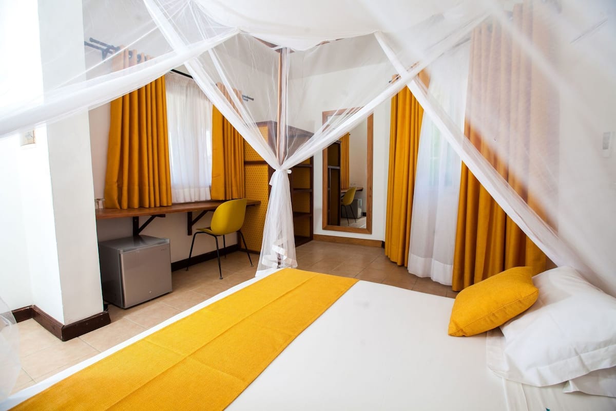 Una habitación de hotel con cama, escritorio, silla y espejo.