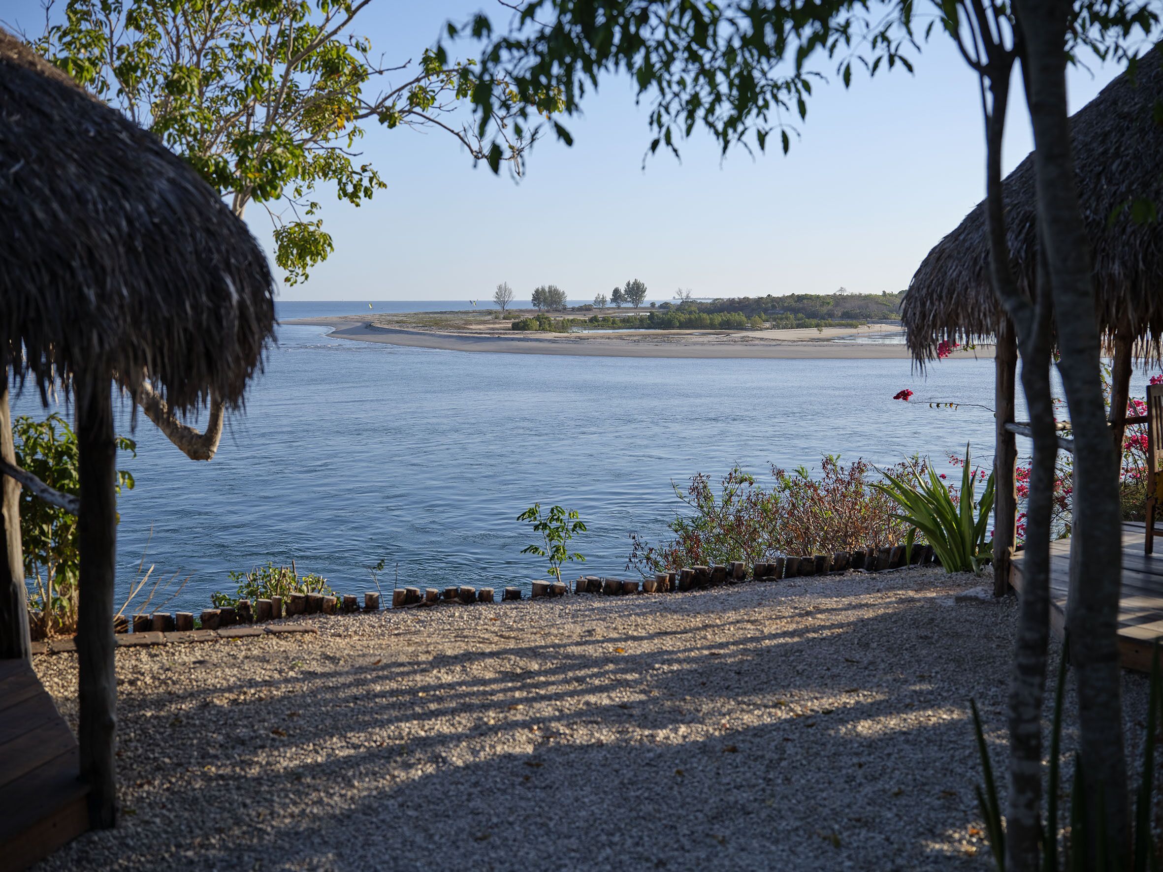 A beach view with thatched umbrellas and a gravel path leading to the water.