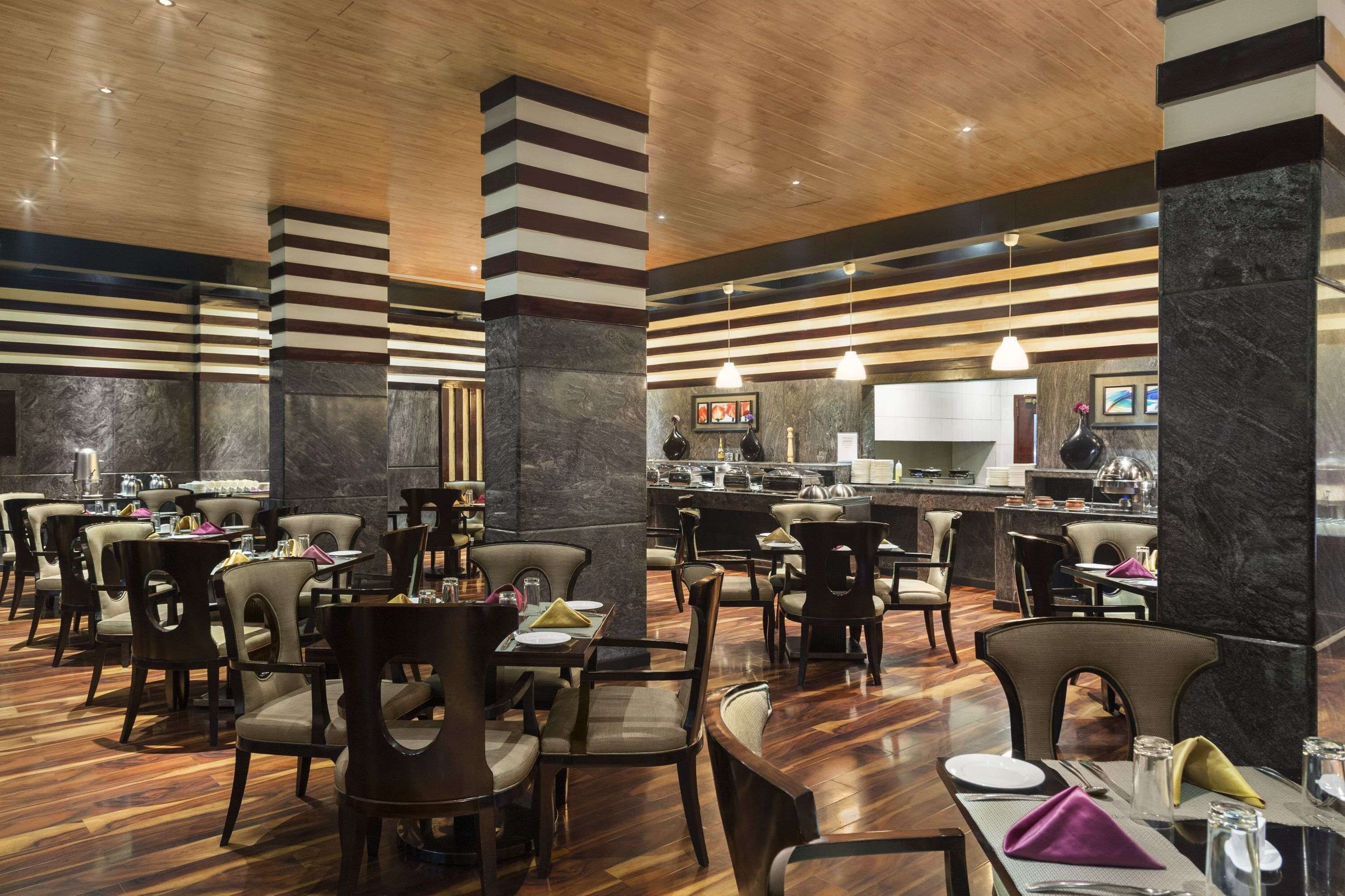 A spacious restaurant with high ceilings, striped columns, and a modern design.