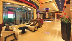 A modern lobby with a curved ceiling, seating area with sofas and armchairs, a large window, and a potted plant. - Ramada by Wyndham Alleppey (Ambalapuzha)