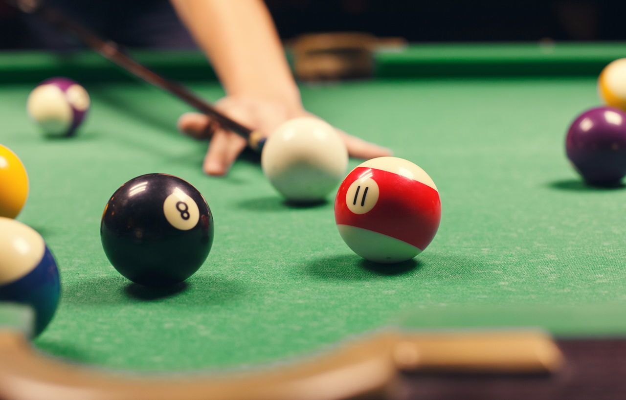 A pool table with billiard balls and a cue stick.