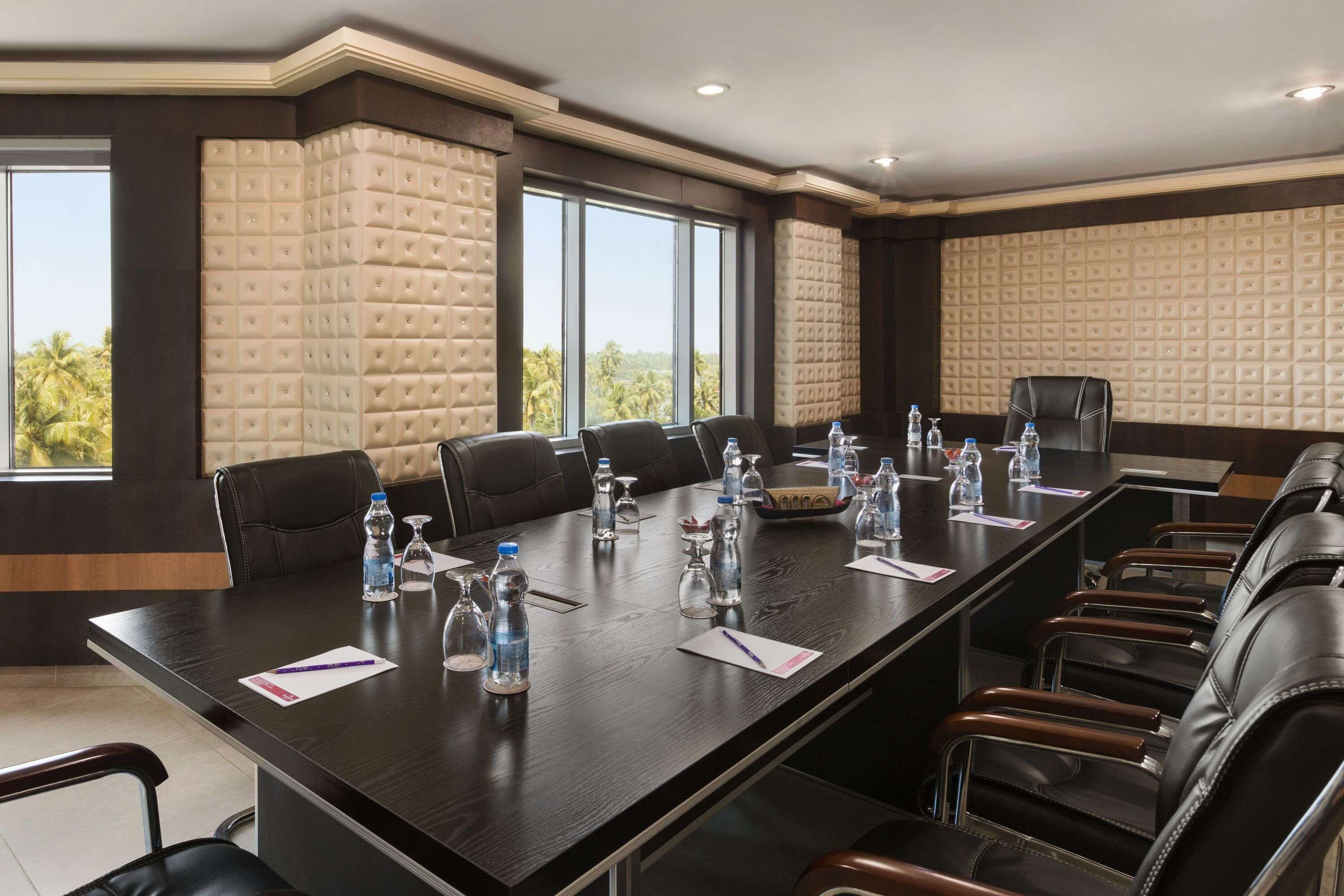 Une salle de conférence avec une longue table, de nombreuses chaises, des bouteilles d’eau et des documents.