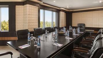 A conference room with a long table, multiple chairs, water bottles, and papers.