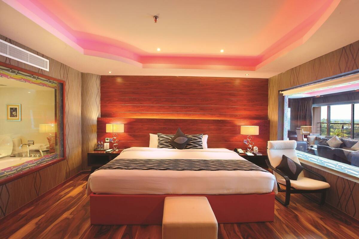 A hotel room with a large bed, a desk, and a view of the outdoors.