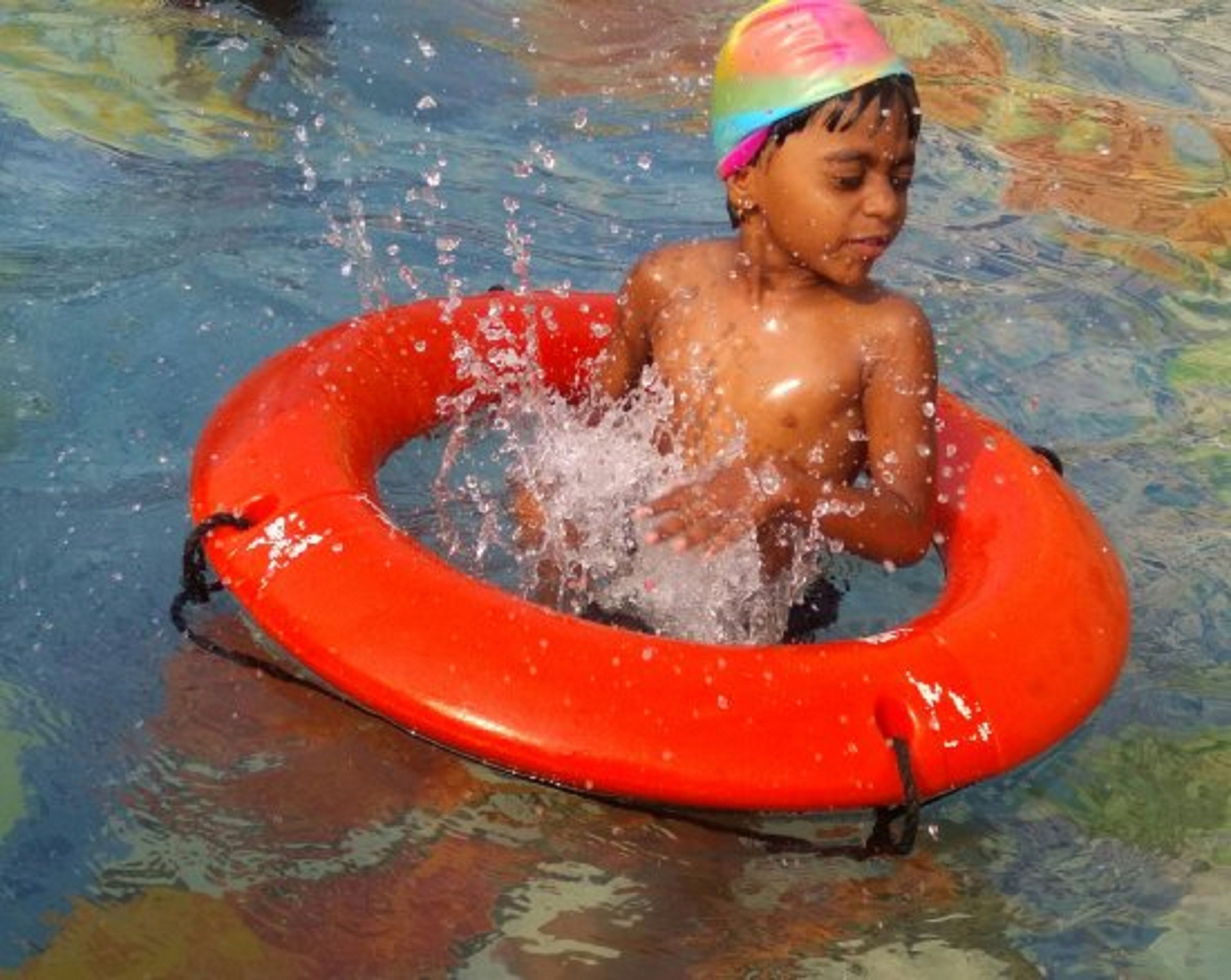 A child in a swimming pool with a red inflatable ring.