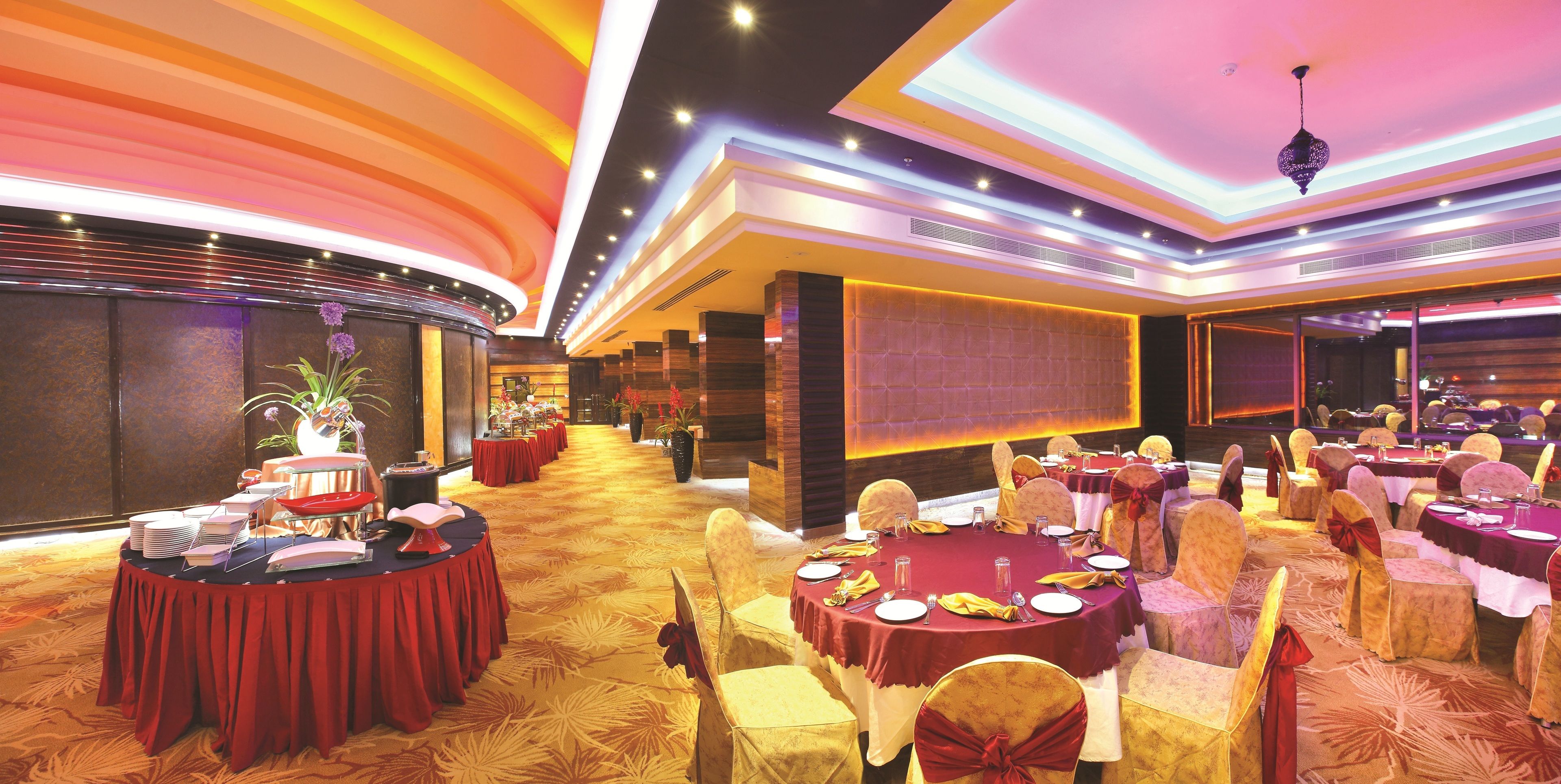 Un salón de banquetes con mesas redondas, sillas y un escenario.