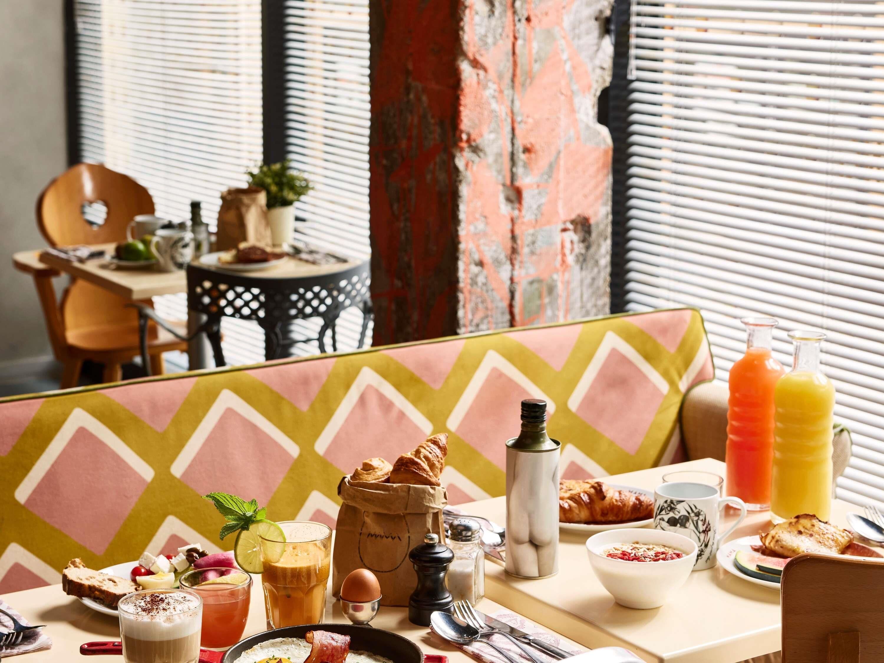 A breakfast setting with a table, chairs, and a window with blinds.