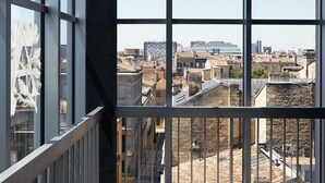 Vista desde un balcón con amplios ventanales que dan a un paisaje urbano.