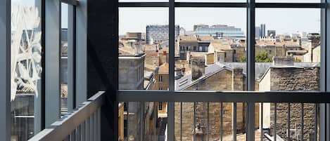 Une vue depuis un balcon doté de grandes fenêtres donnant sur un paysage urbain.