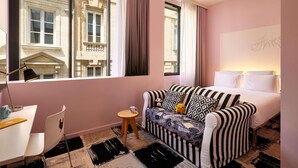 Una habitación de hotel con un ventanal grande, una cama, un sofá, un escritorio y una silla.