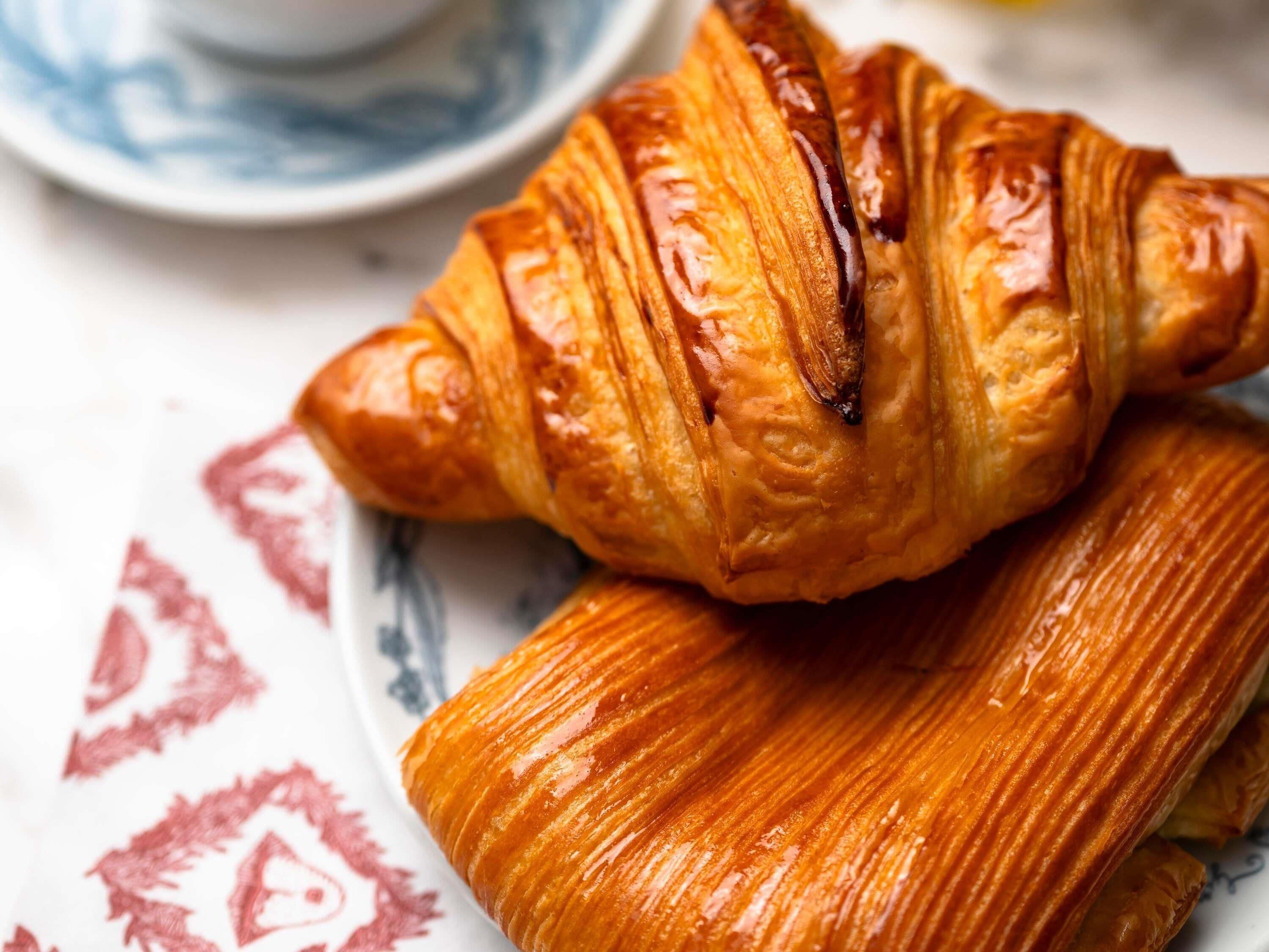 A croissant and a pastry on a plate with a floral pattern.