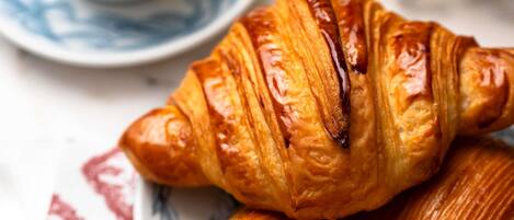 A croissant and a pastry on a plate with a floral pattern.