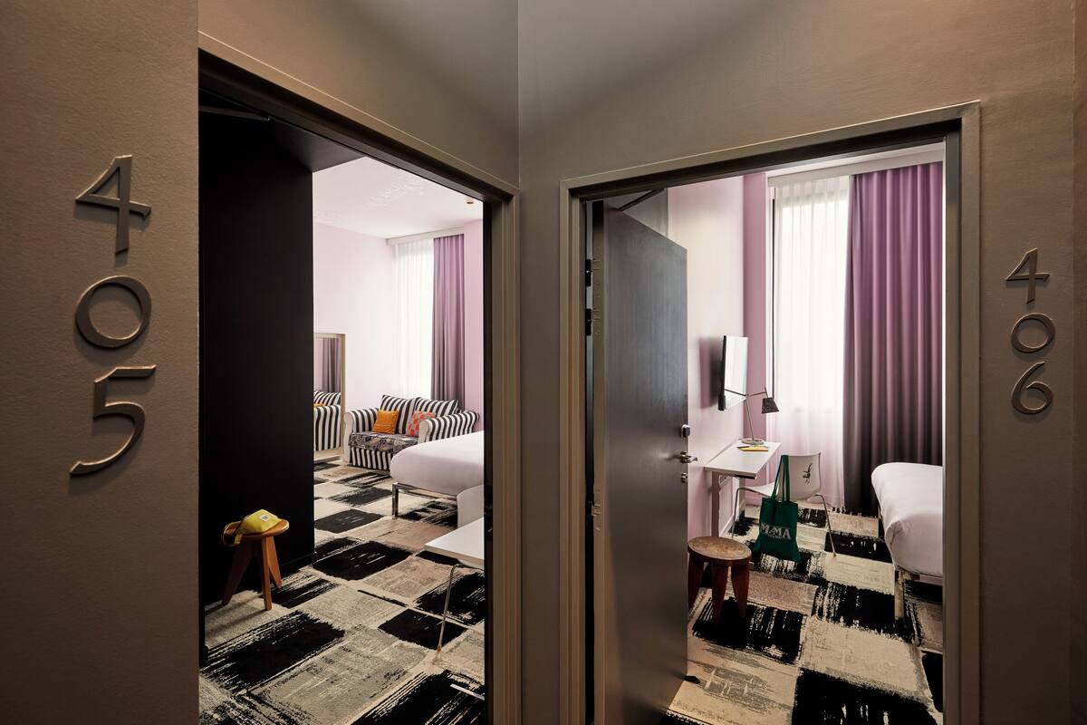 Een hotelkamer met een geruit vloerkleed, een bed, een bureau en een stoel.