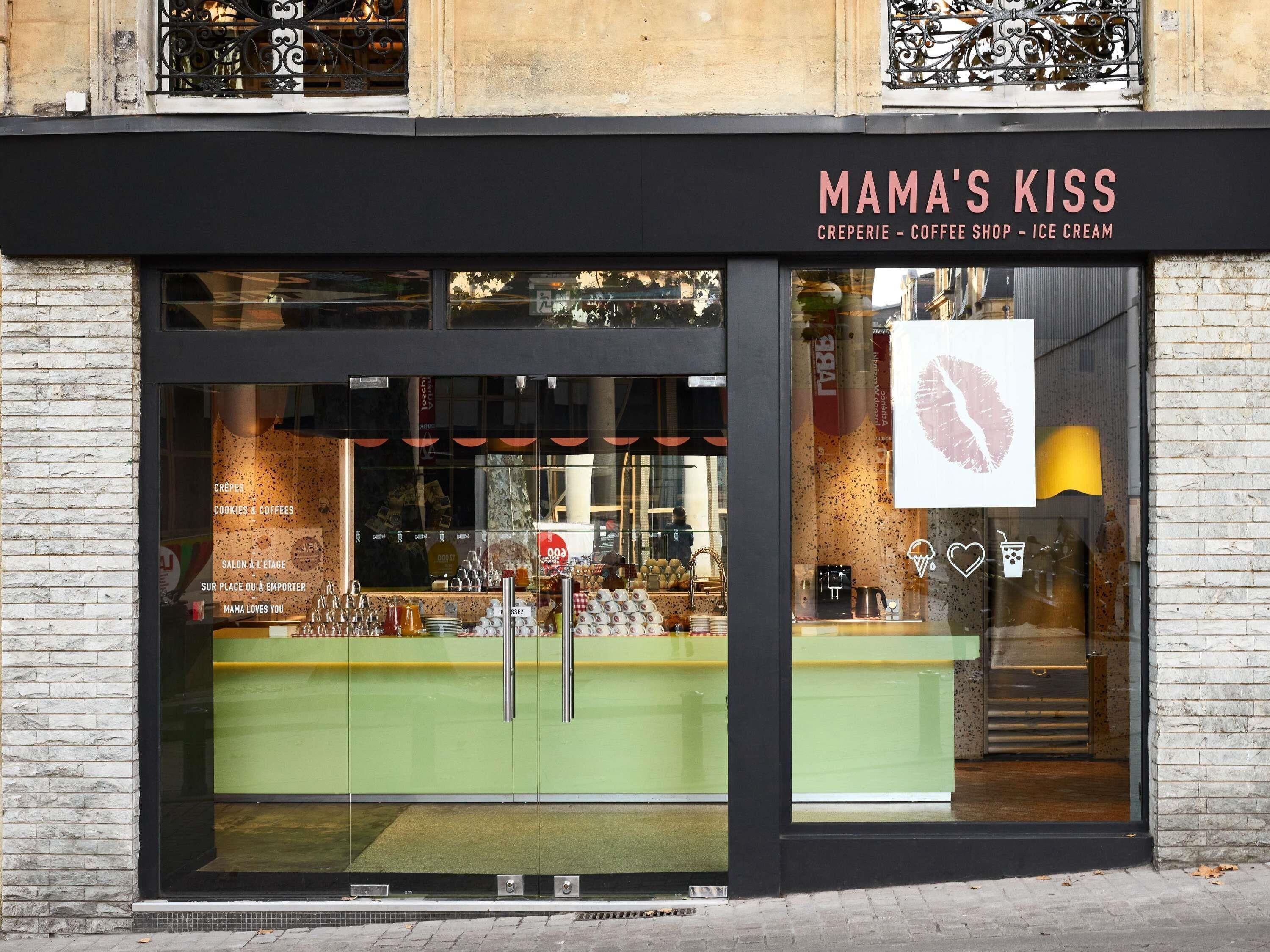 A storefront with a sign reading 'MAMA'S KISS' and a large window displaying various items.