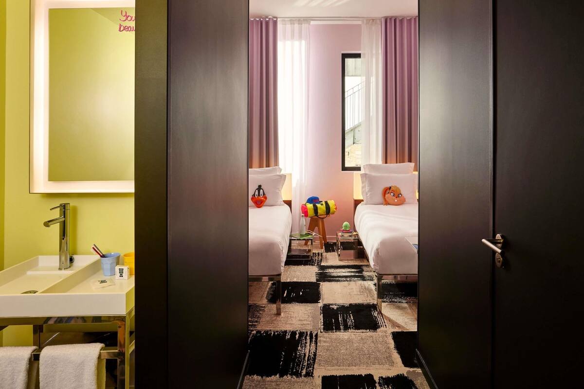 Een hotelkamer met een spiegelwand, een wastafel, een bed met een kussen, en een geruit tapijt.