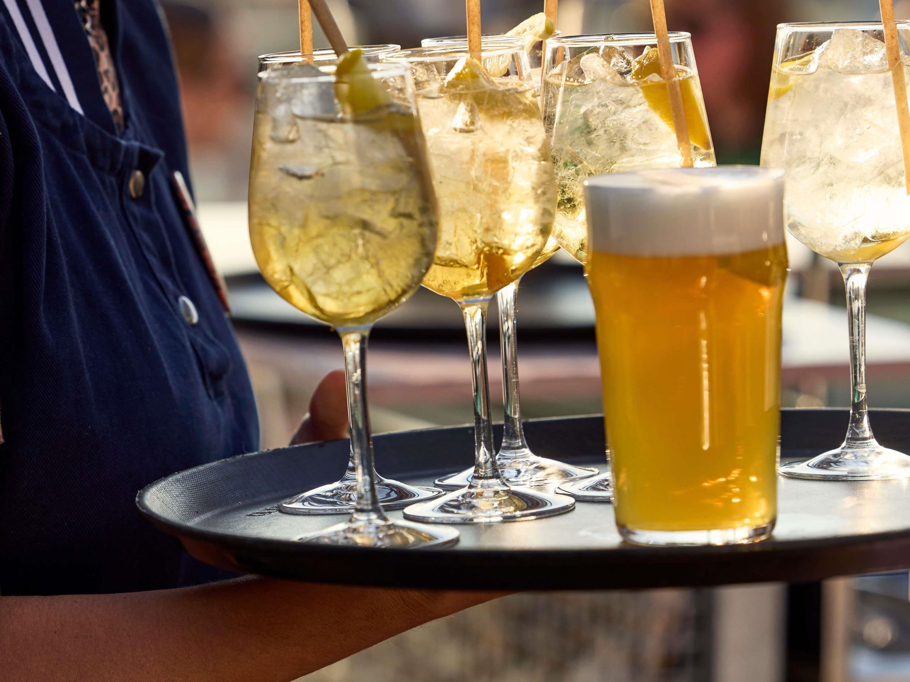 Een dienblad met verschillende bierglazen en een fles, waarschijnlijk in een buitenterras.
