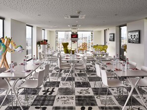 Een moderne hotelkamer met een geruite vloer, witte meubels en uitzicht over de stad.