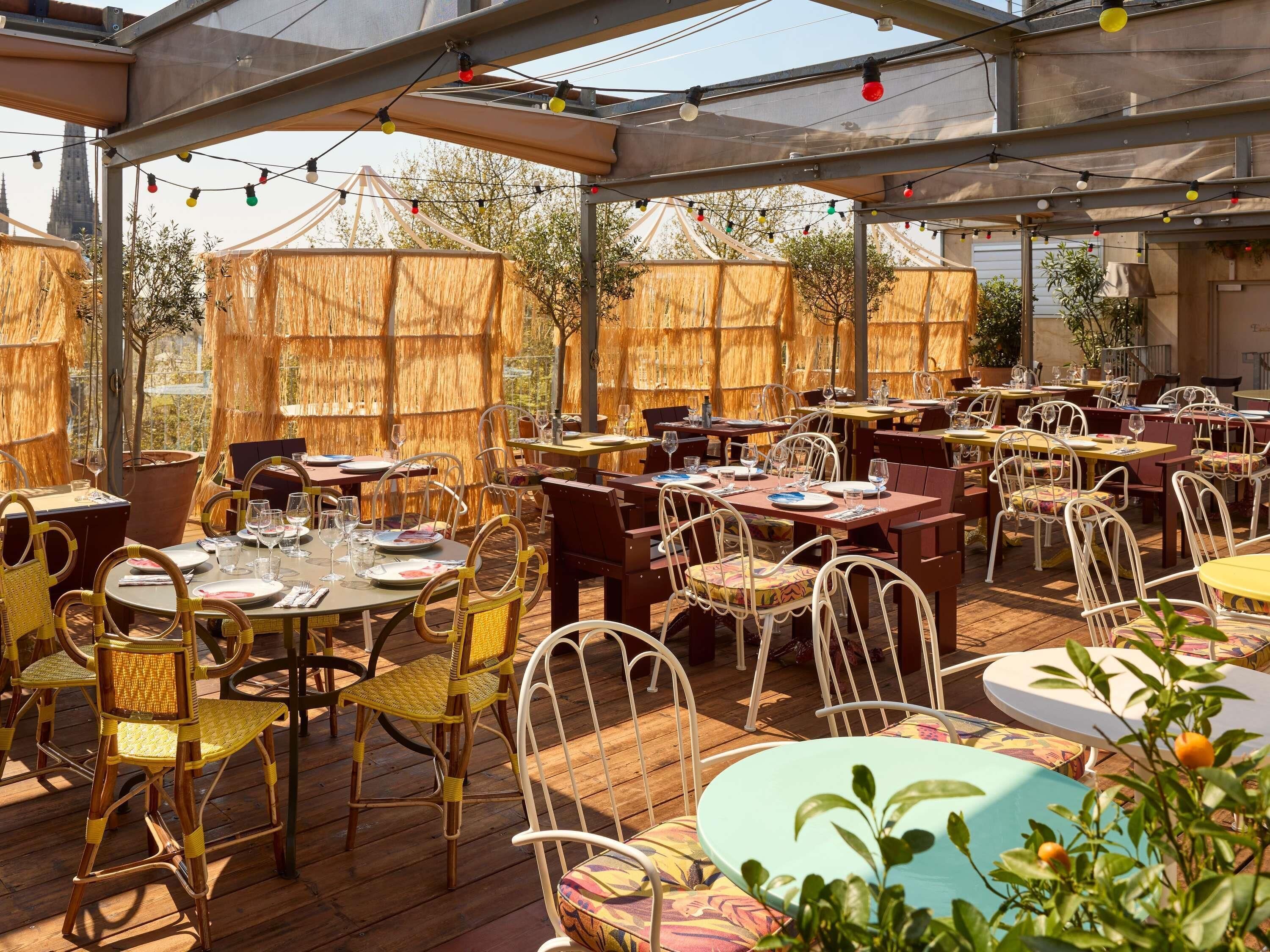 An outdoor dining area with tables and chairs, covered by a transparent roof, and surrounded by wooden fences.