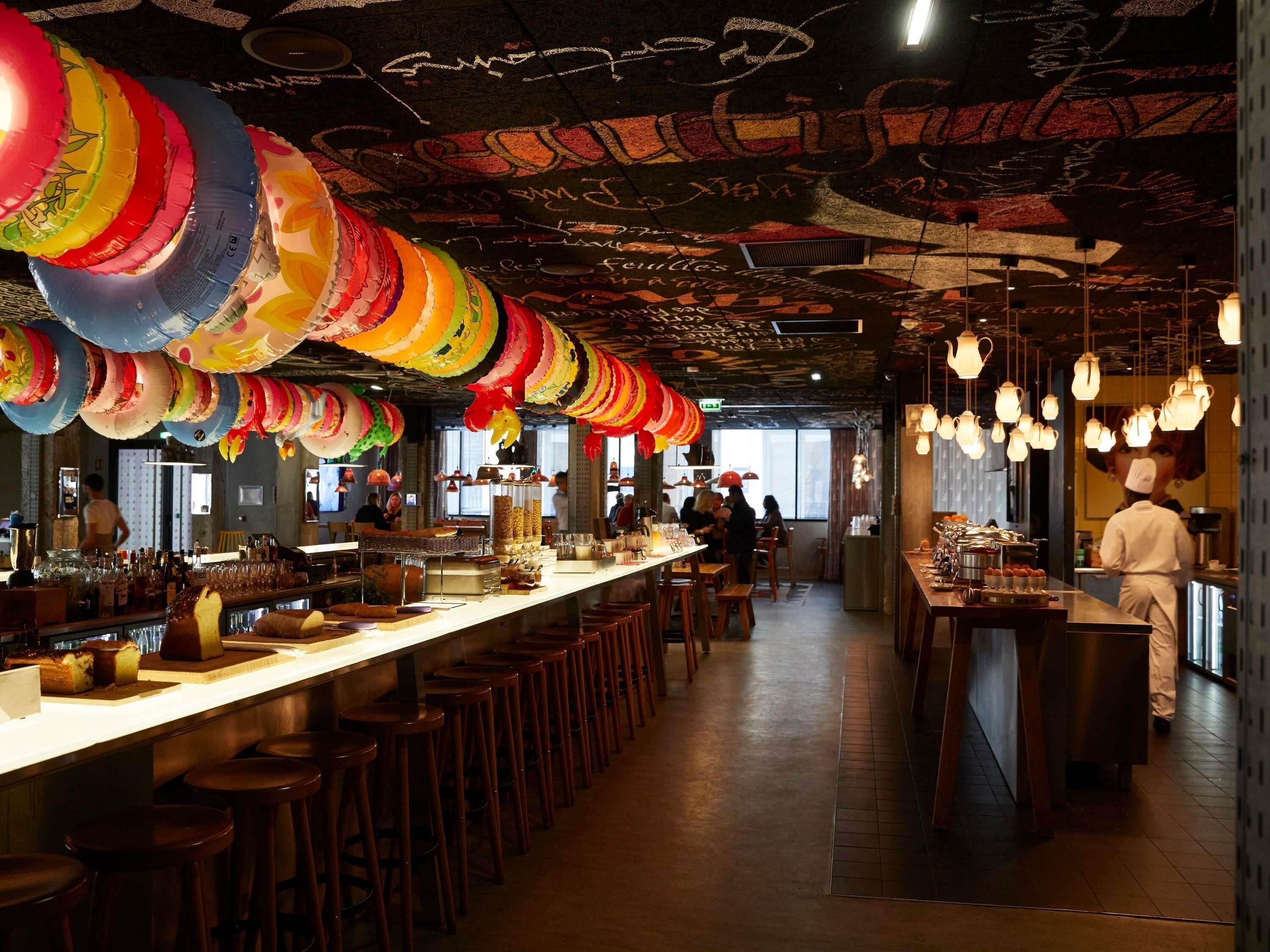 Ein Restaurantinneres mit einer langen Theke, Hockern, hängenden Leuchten und einer Bar.