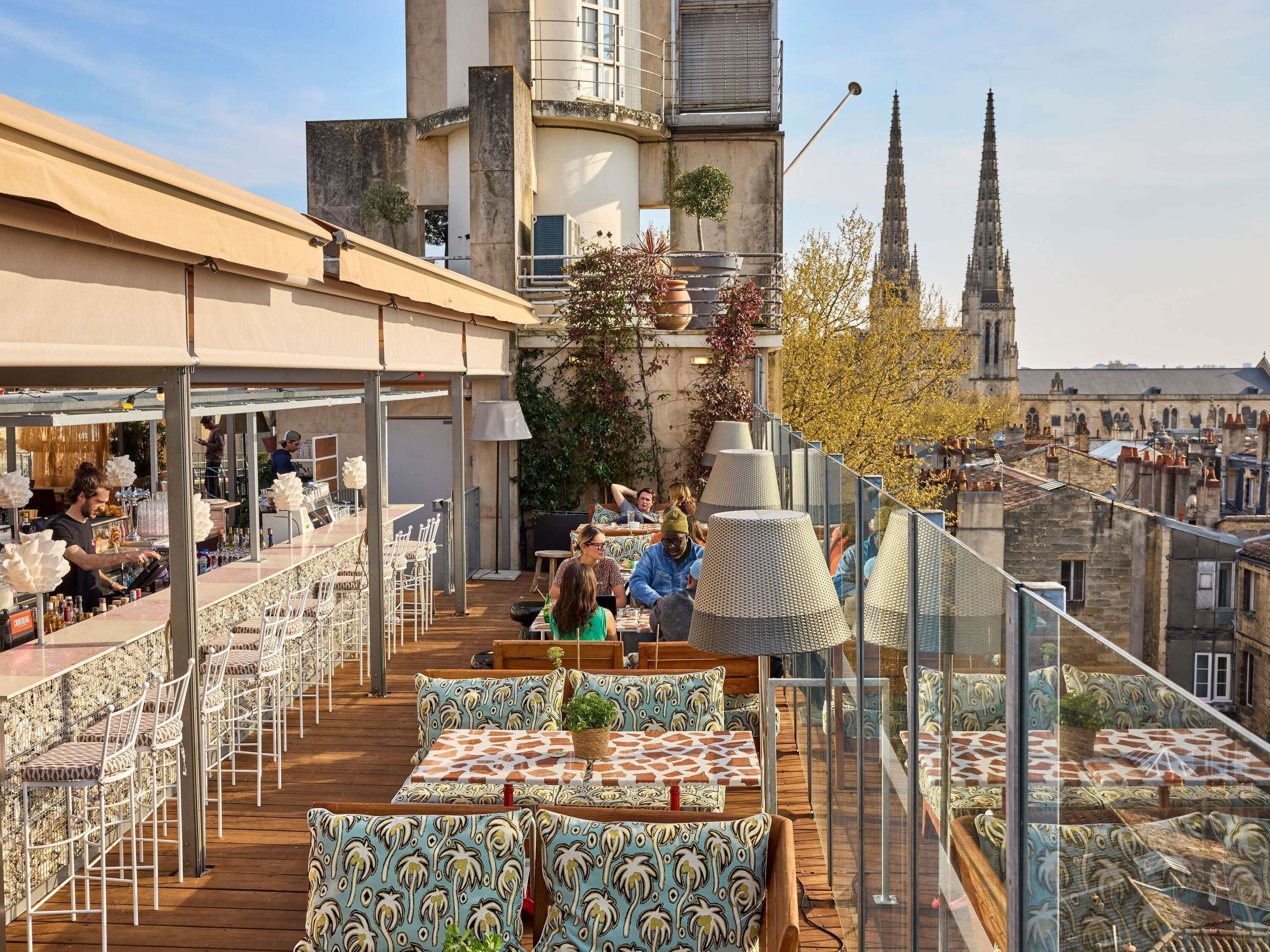 Een terras buiten met zitplaatsen, een bar en uitzicht op een kathedraal.