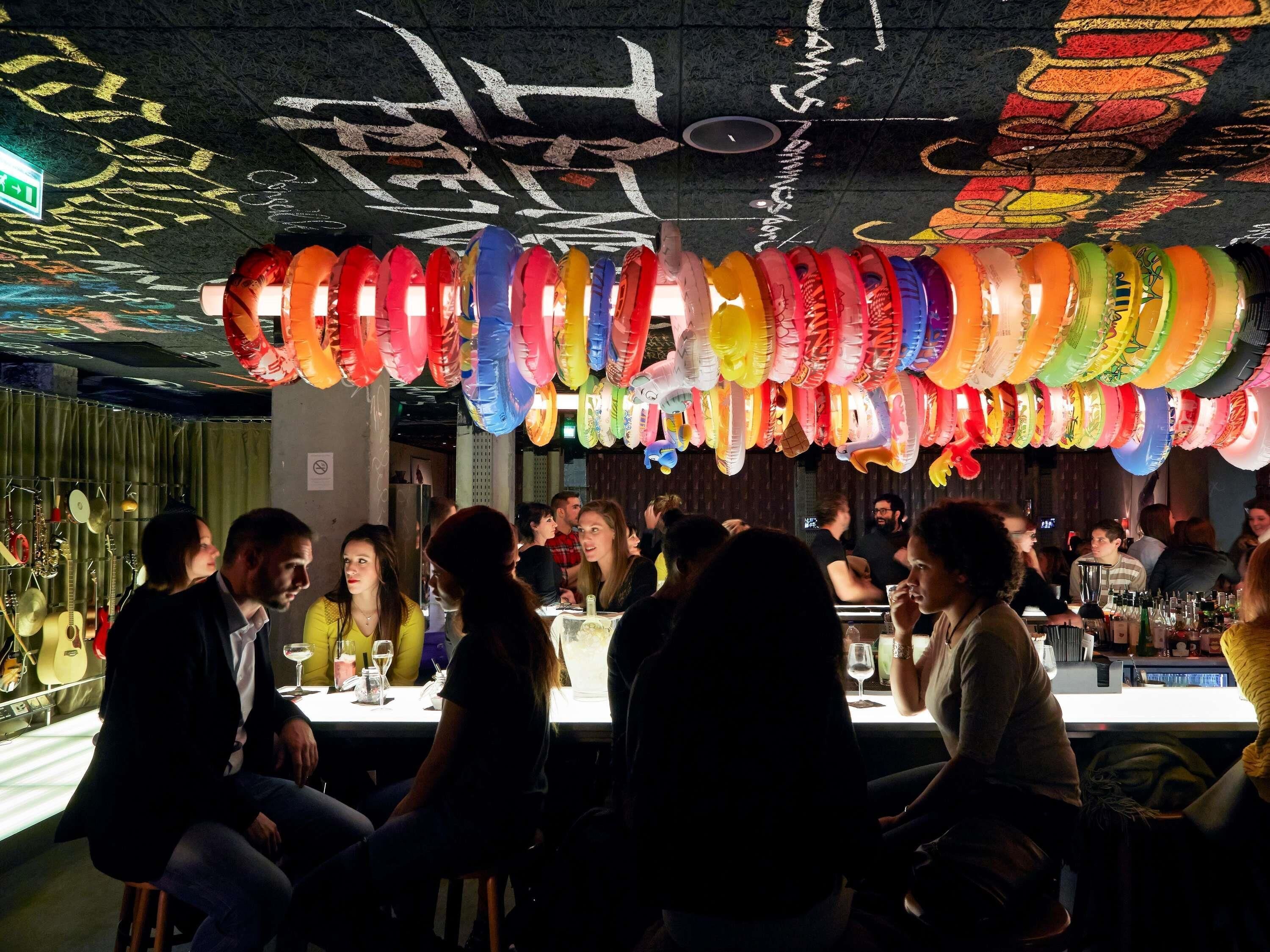 Un restaurant avec des tables et des chaises, un plafond couvert de graffitis et des décorations suspendues.