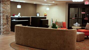 A reception area with a reception desk, a large seating area, and a decorative vase.