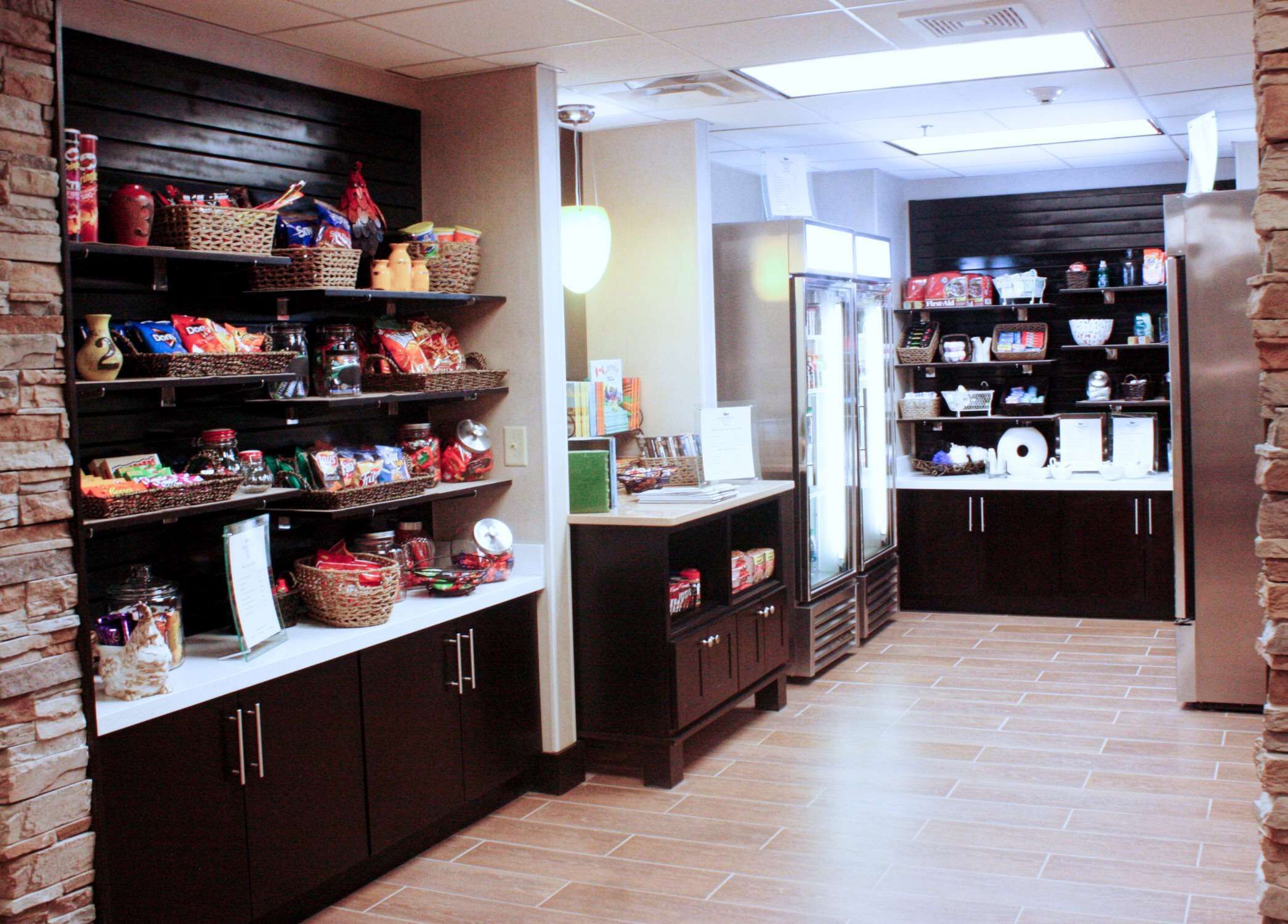 A kitchen area with shelves stocked with snacks and beverages, a refrigerator, and a microwave.