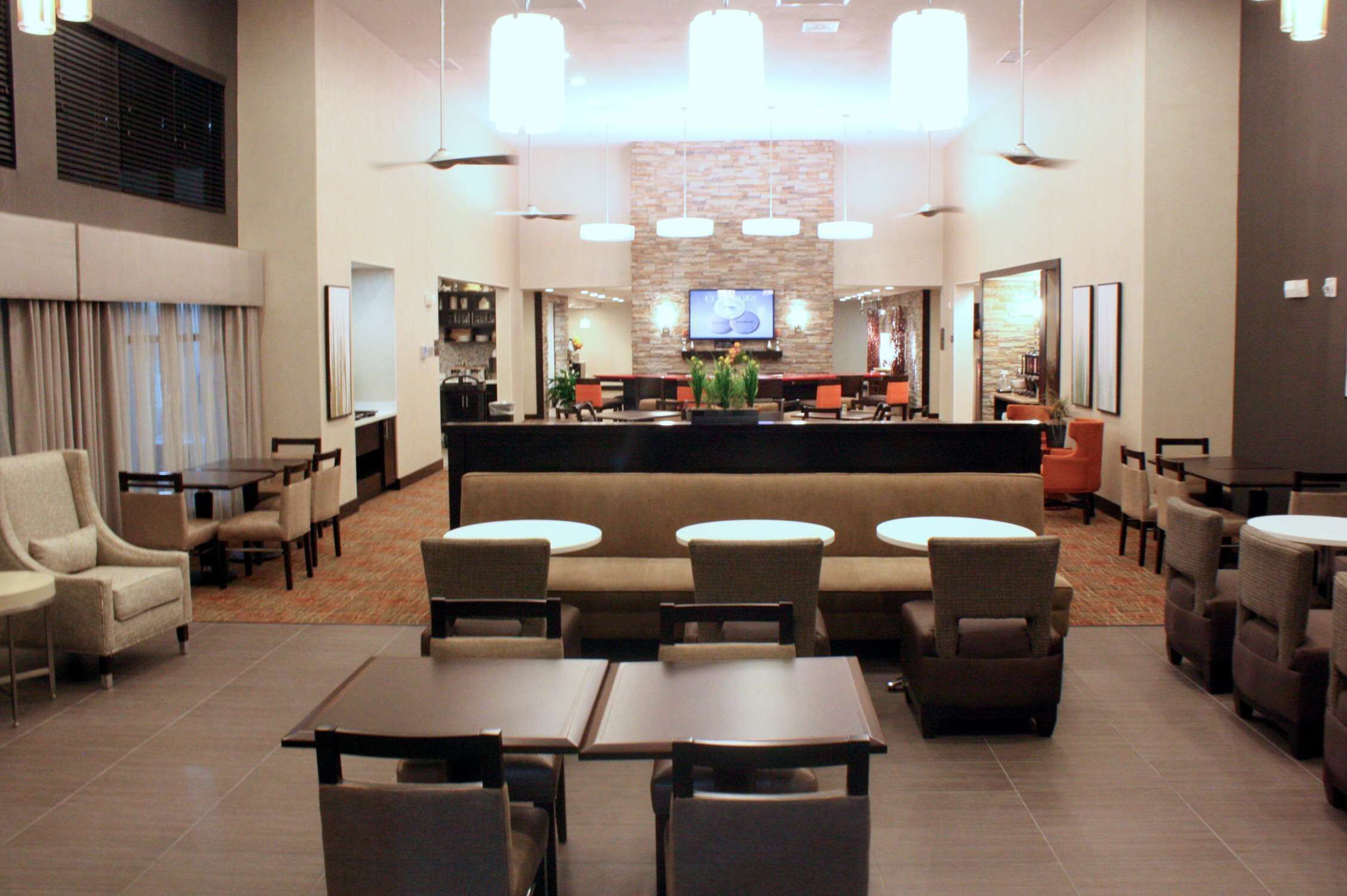 A hotel lobby with a reception desk, seating area, and a television screen.
