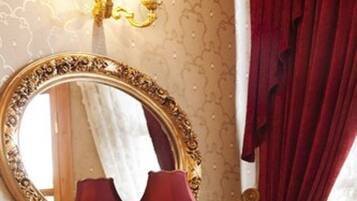 A mirror with an ornate frame, a wall-mounted light fixture, and a red curtain.