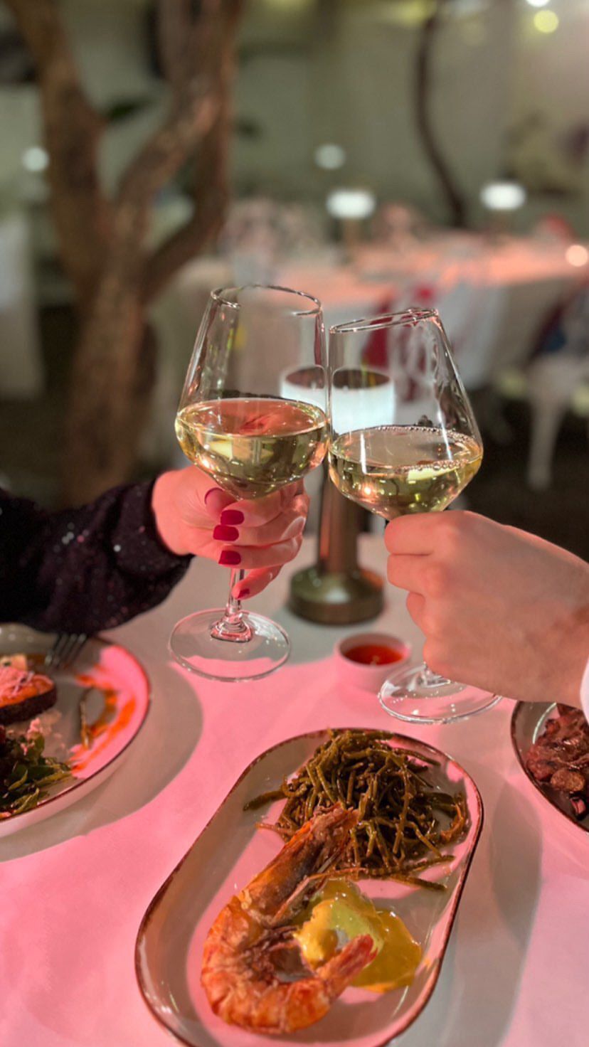 Una mesa de comedor con platos de comida y dos copas de vino chocando.