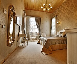 A classic hotel room with a large bed, a sitting area with chairs, a desk, and a large ornate mirror. - Ada Palas Buyukada (Adalar)