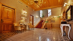 A grand lobby with a checkered floor, a staircase, and a chandelier.