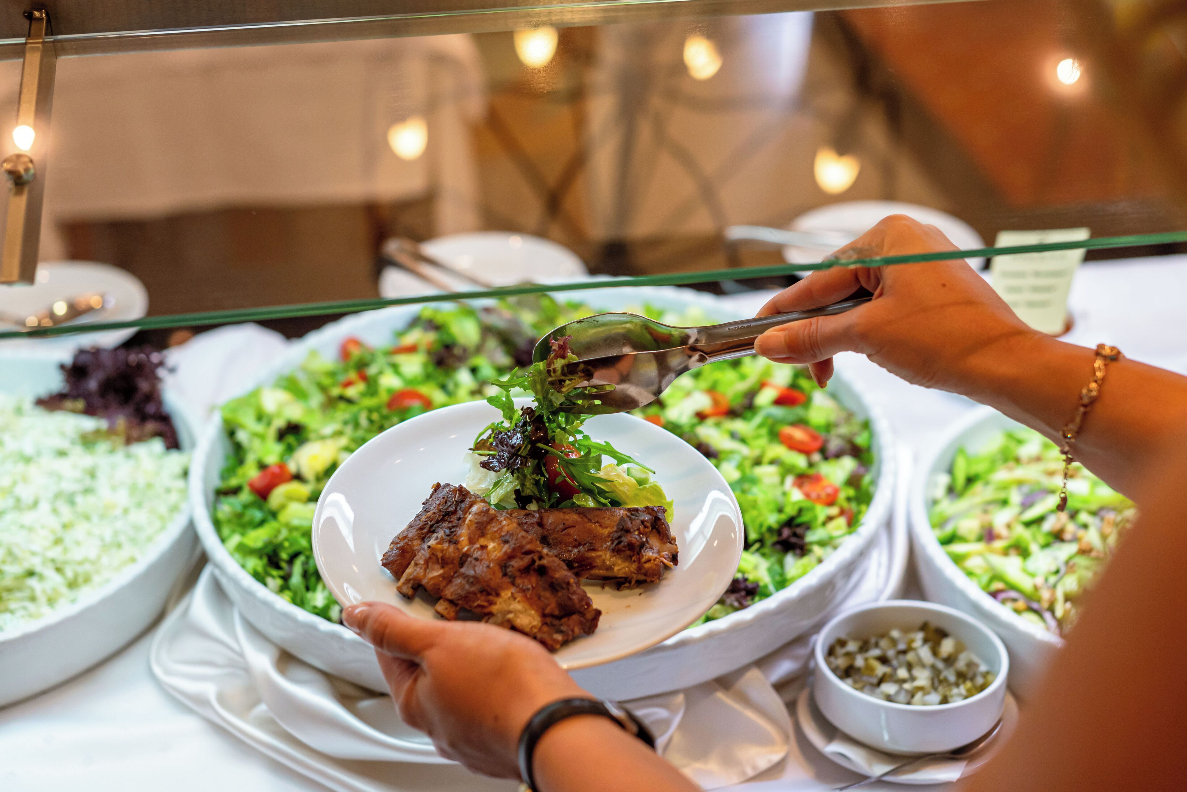 Un buffet proposant divers plats, notamment des salades, des viandes et un petit assortiment de condiments.