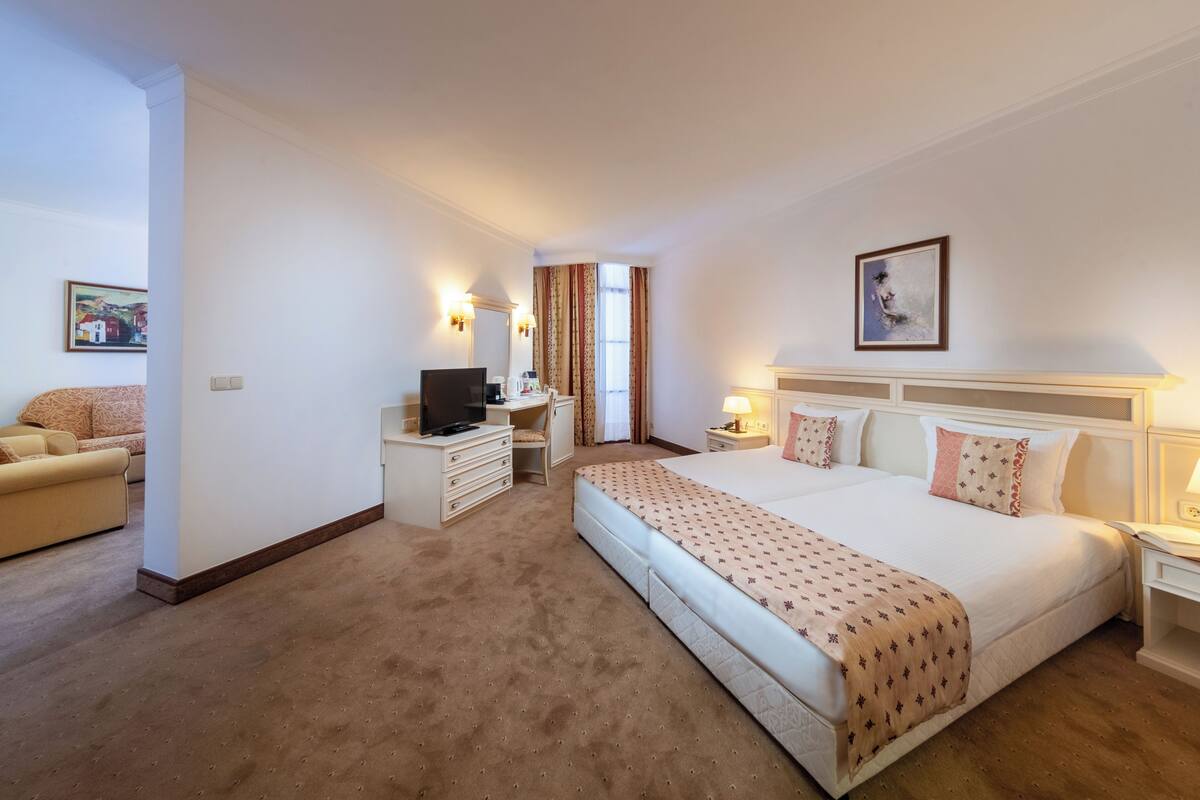 Una habitación de hotel con una cama grande, un escritorio con una computadora, una silla y un sofá.