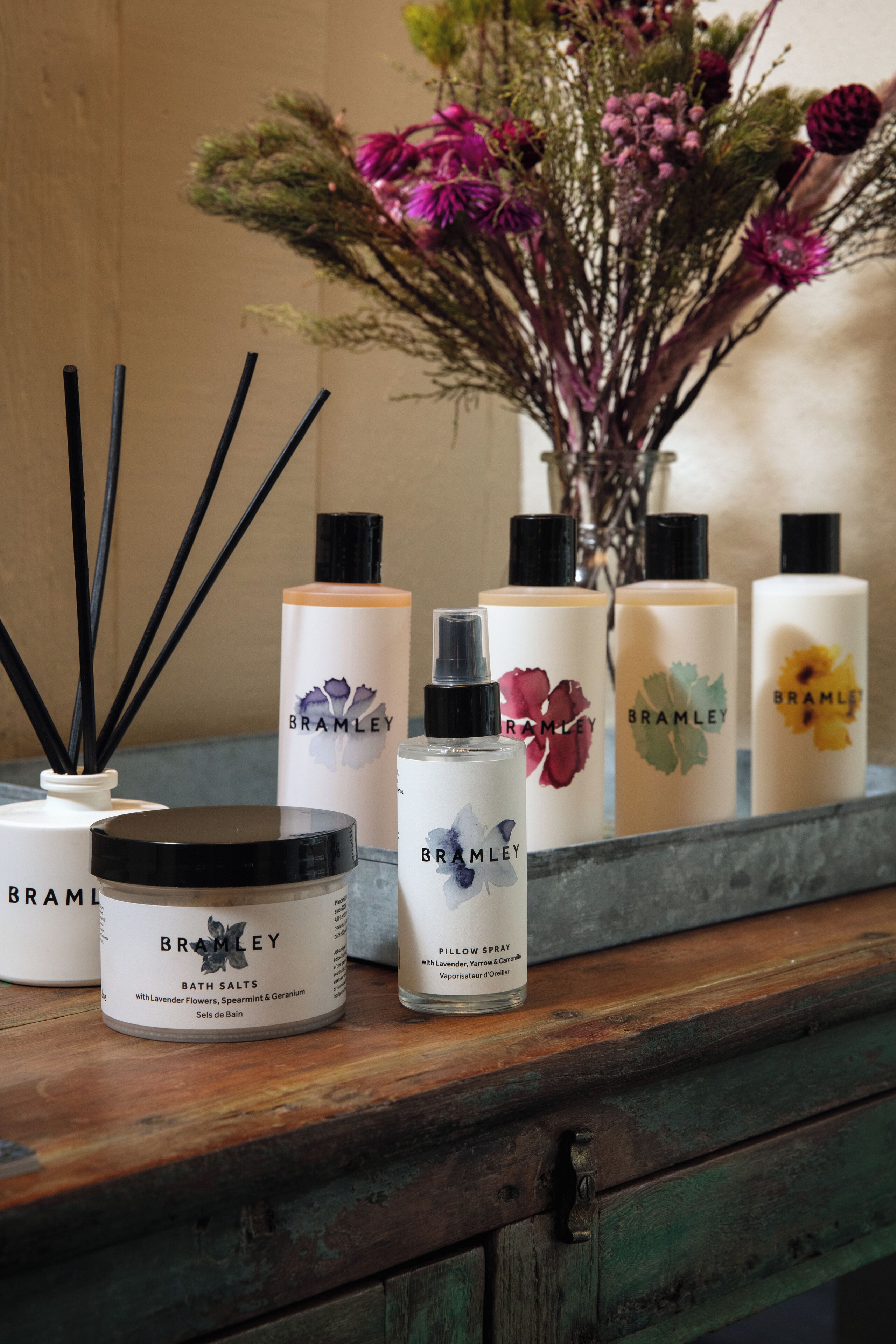 A selection of Brambley bath salts and a spray bottle on a wooden surface.
