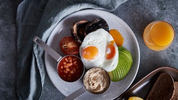 Un plato con huevos, frijoles, aguacate y tostadas sobre una superficie gris.