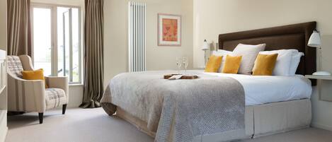 A bedroom with a large bed, a chair, a window with curtains, and a radiator.