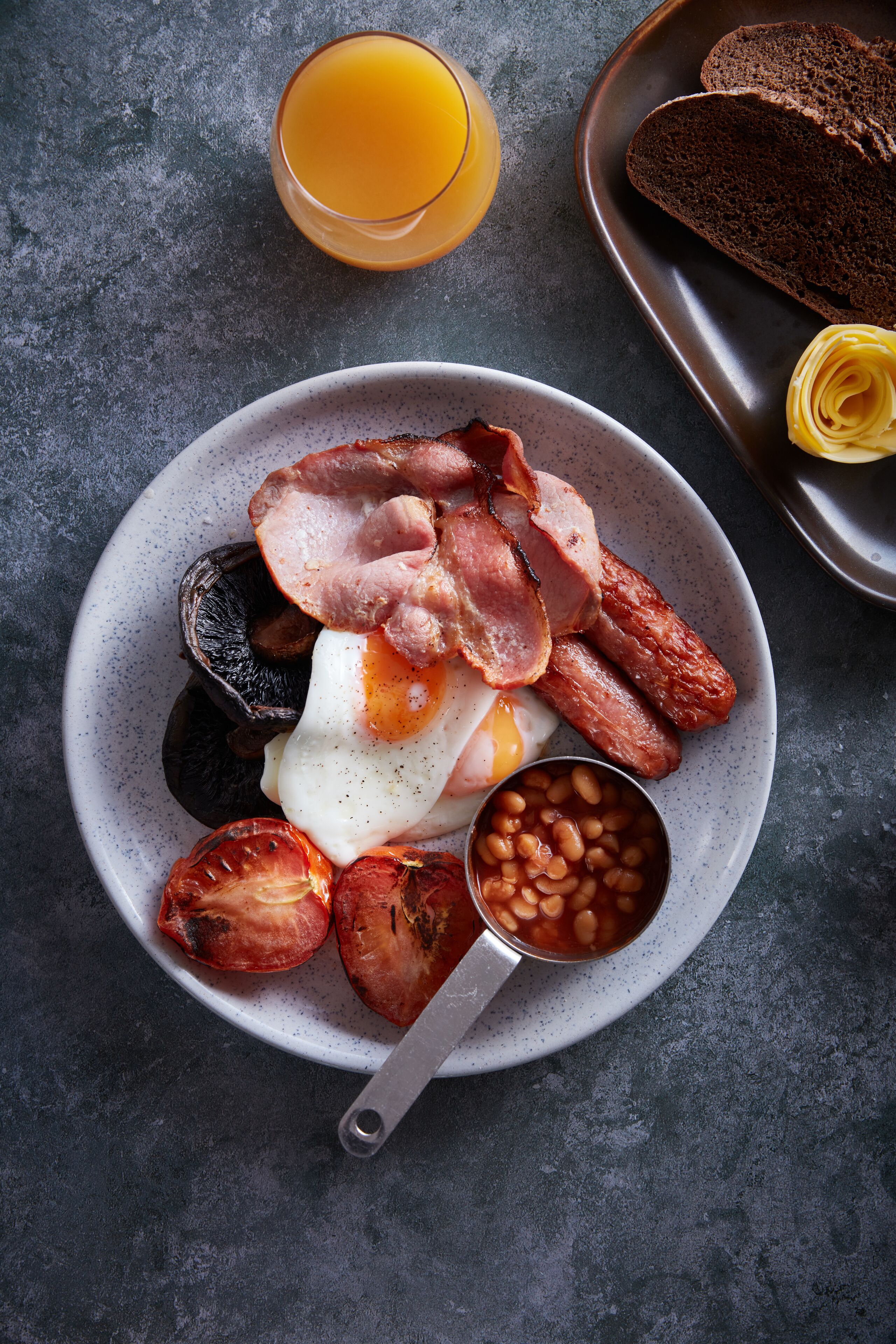 A breakfast plate with bacon, eggs, tomatoes, and beans.